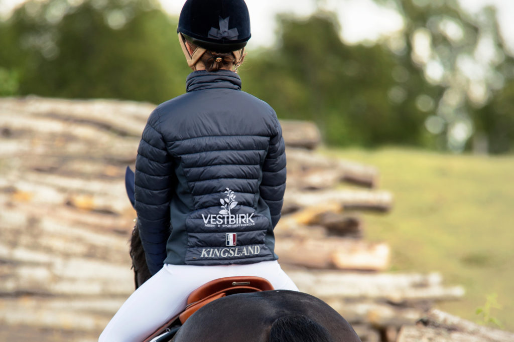 Rytter på hest iført Kingsland jakke med VMSE logo på ryggen.